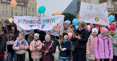 Grupa ludzi z balonami, transpartentem idzie ulicami Poznania