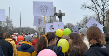 Grupa ludzi z balonami, transpartentem idzie ulicami Poznania